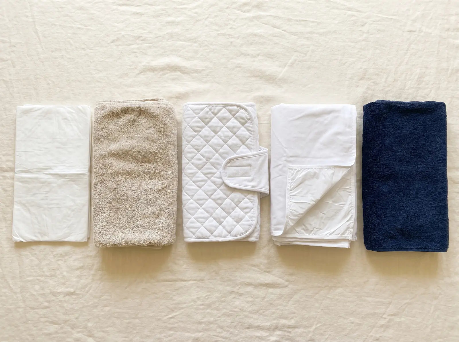 Flat lay of five postpartum bedding workaround products in a row